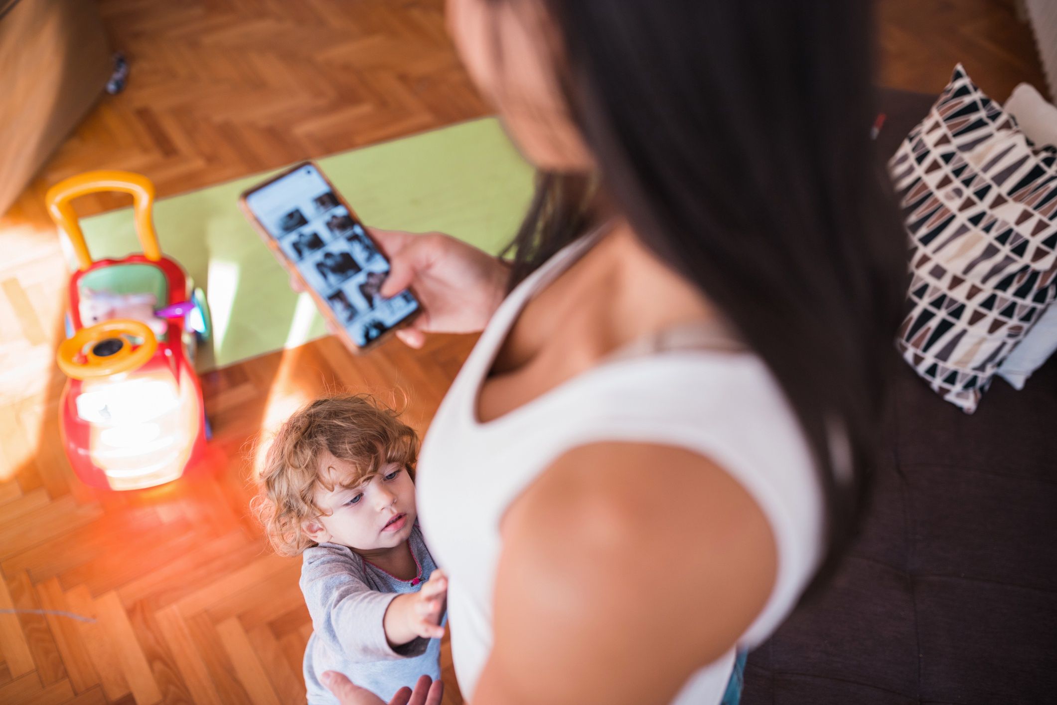 Toddler approaching woman looking at photo gallery on mobile phone
Mother using smart phone and toddler wanting to be held
Dobrila Vignjevic