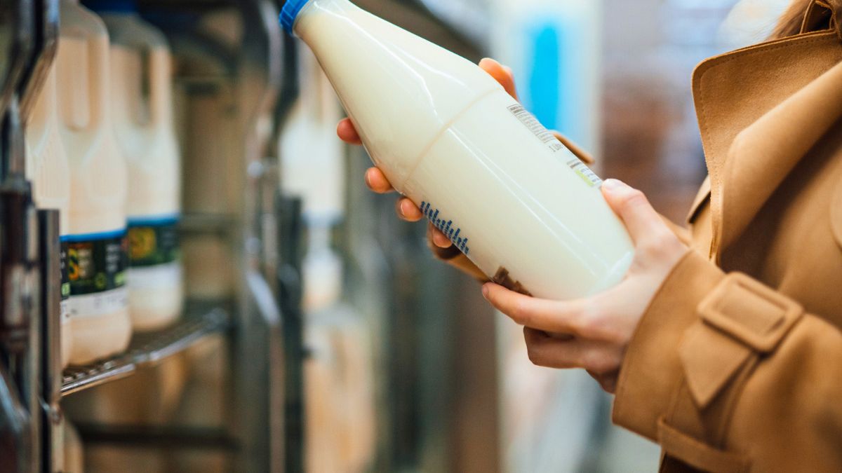 Kobieta bierze butelkę mleka z półki