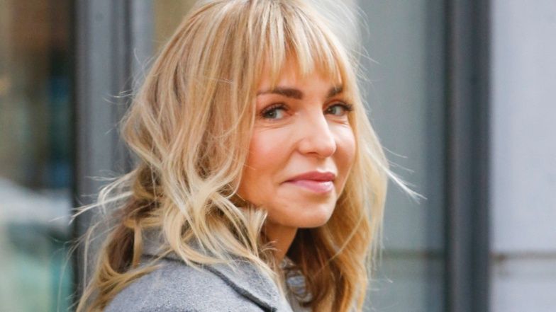 Odmieniona Anna Wyszkoni pozuje przed budynkiem TVN