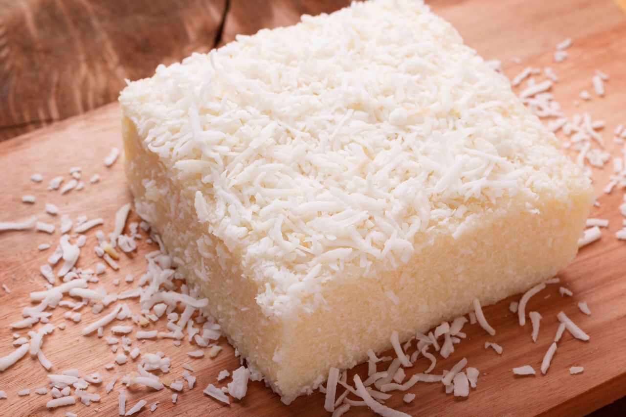 Brazilian traditional dessert: sweet couscous (tapioca) pudding (cuscuz doce) with coconut on wooden board. Selective focus