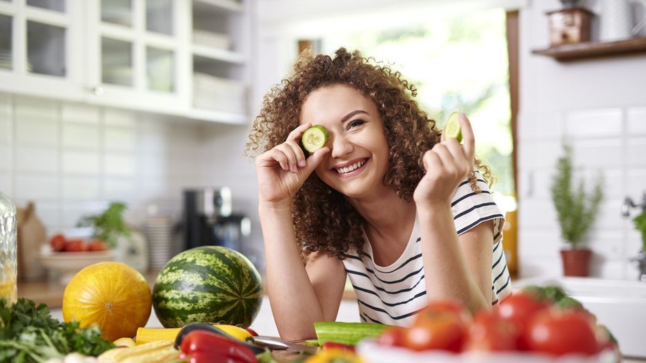 Woman holding a slice of cucumber