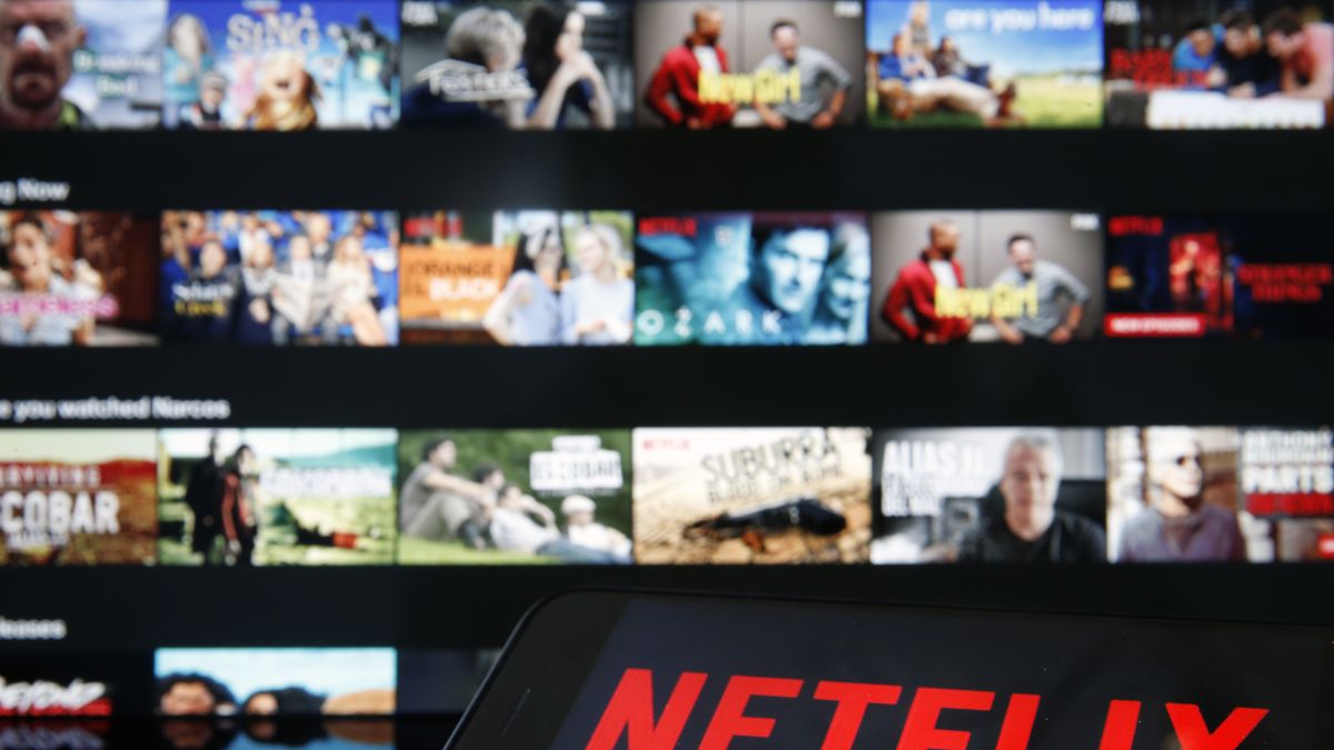 PARIS, FRANCE - MARCH 28: In this photo illustration, the Netflix media service provider's logo is displayed on the screen of an iPhone in front of a television screen on March 28, 2020 in Paris, France. Faced with the coronavirus crisis, Netflix will reduce visual quality for the next 30 days, in order to limit its use of bandwidth. (Photo by Chesnot/Getty Images)
