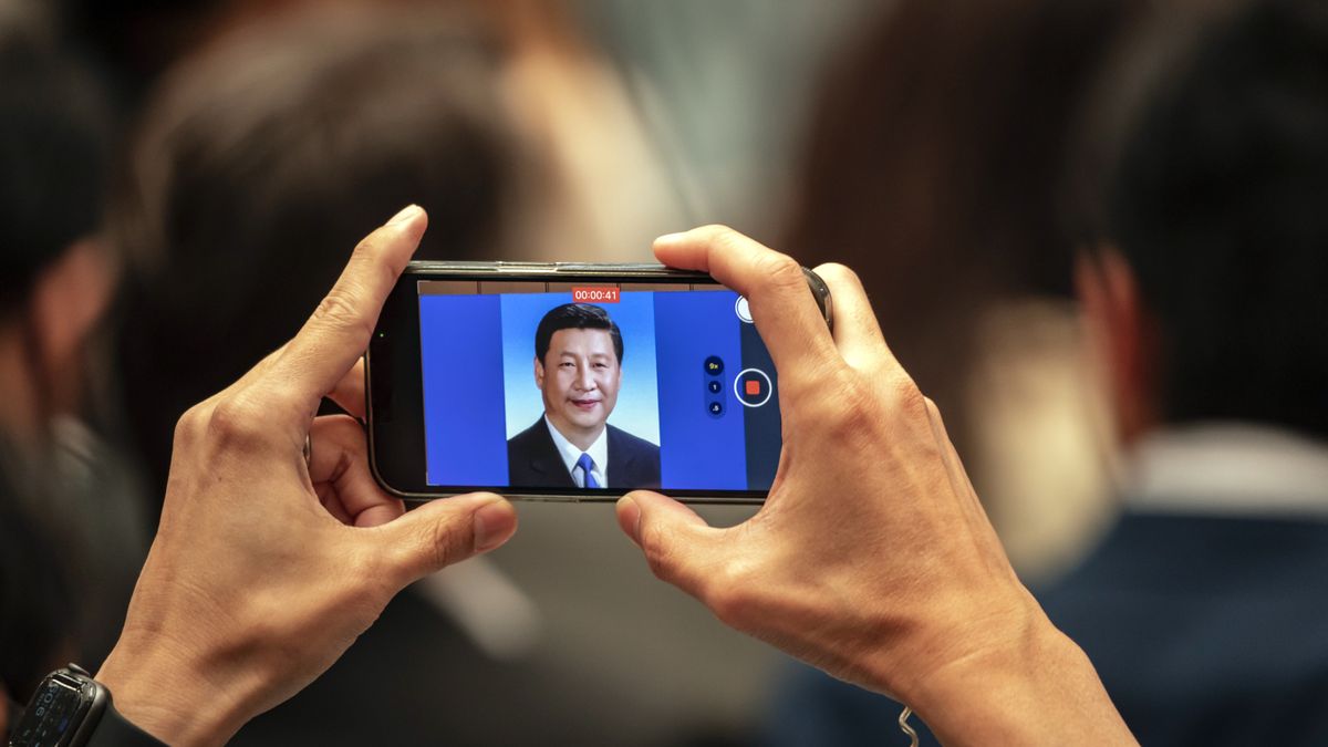 An attendee takes a photograph of a portrait of Chinese President Xi Jinping as Qin Gang, China's foreign minister, not pictured, speaks during the Lanting Forum in Shanghai, China, on Friday, April 21, 2023. Recent allegations that China undermines peace and stability of the Taiwan Strait run against historical and international common sense, Qin said. Photographer: Qilai Shen/Bloomberg via Getty Images