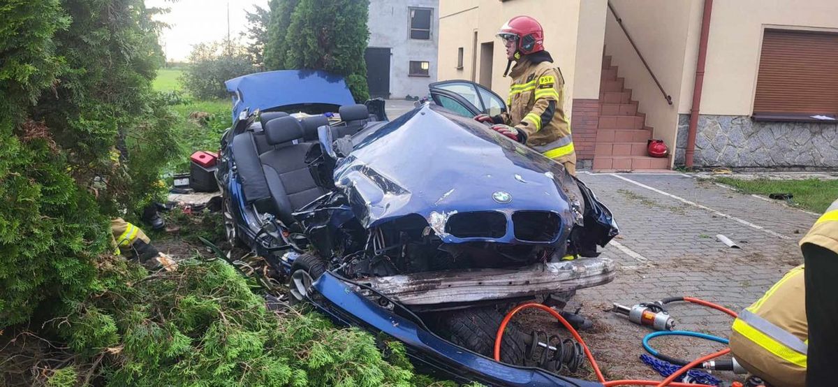 BMW, wypadek, policja BMW uderzyło w betonowe ogrodzenie. Pasażera z wraku uwalniali strażacy