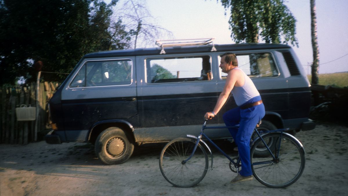 Lech Wałęsa jedzie rowerem na tle Volkswagena, który aktualnie jest do sprzedania