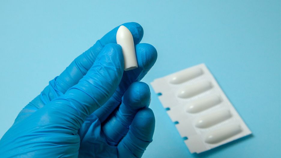 Suppository for anal or vaginal use in the hands of doctor in gloves. Candles for treatment of hemorrhoids, temperature, thrush, inflammation