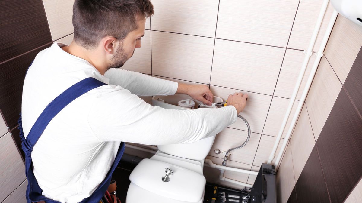 Hydraulik naprawia zbiornik toalety.