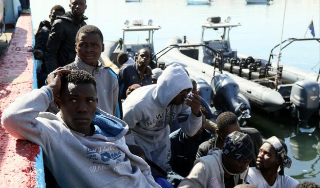Migranci czekają w dokach Tripolisu po tym, jak ich łódź zatonęła niedaleko wybrzeża