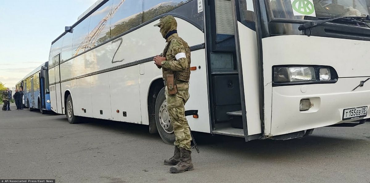 Rosyjski żołnierz pilnuje autobusu z ukraińskimi żołnierzami