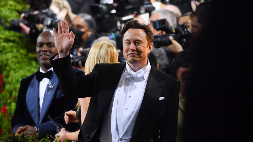 Na zdjęciu Elon Musk podnoszący rękę w górę