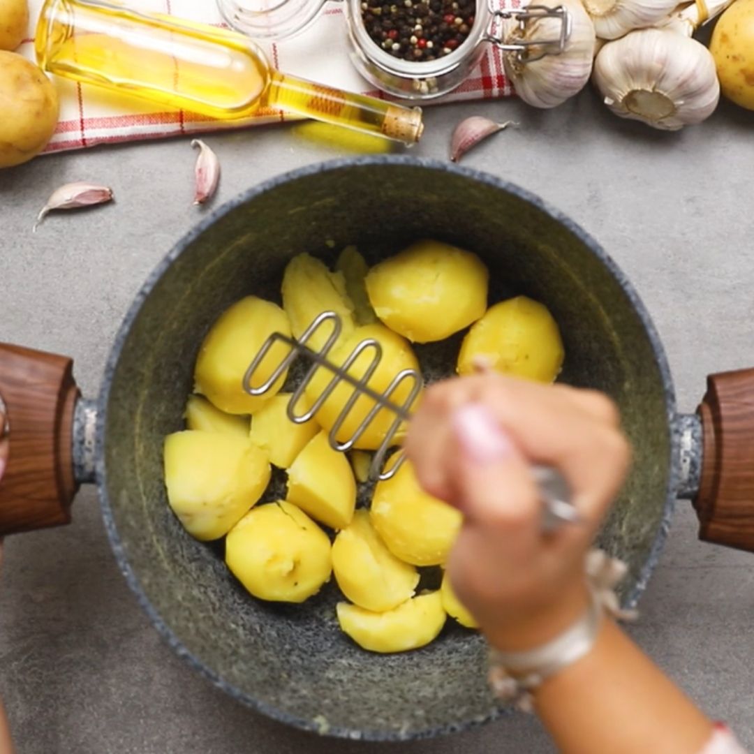 I mash the boiled potatoes using a masher.