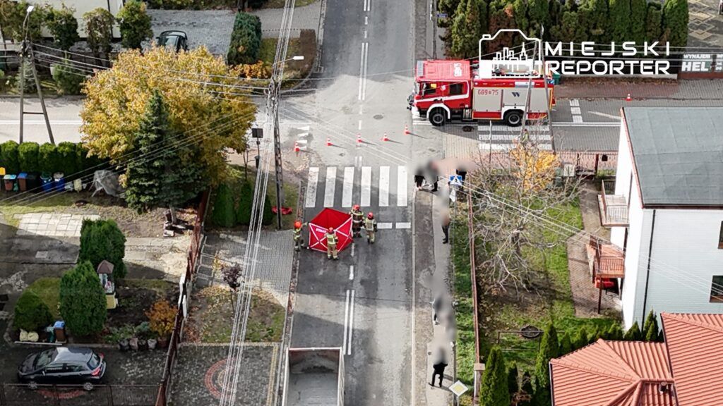 Strażacy w hełmach ustawiają czerwony namiot na przejściu dla pieszych w mieście, podczas akcji ratunkowej.