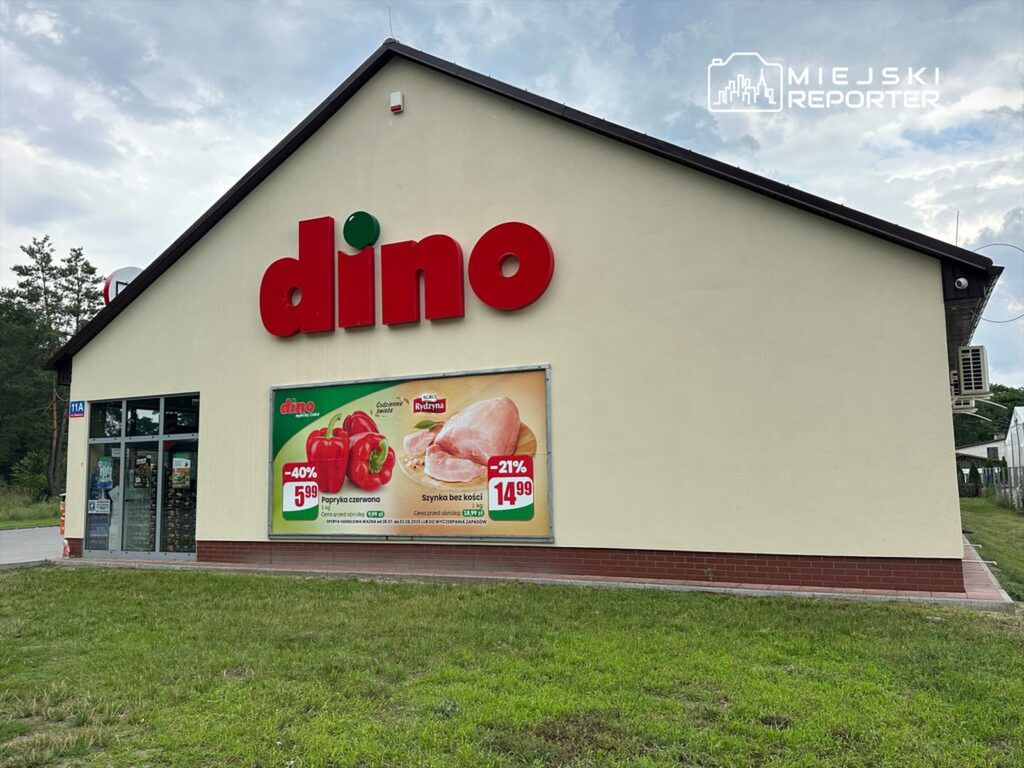 Sklep spożywczy z dużym napisem "dino" na elewacji, z promocjami na paprykę i szynkę na plakacie.
