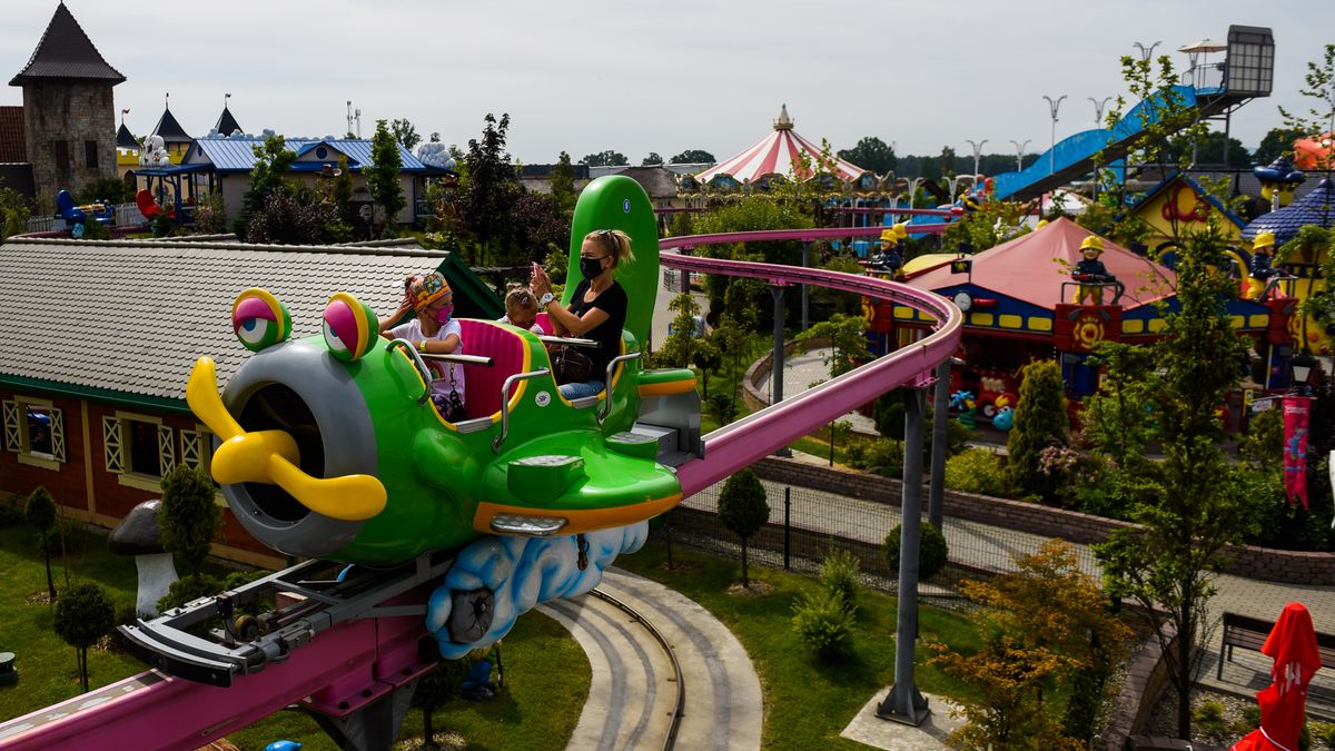 ZATOR, POLAND - JUNE 07 : A family wears protective face masks as they ride a carousel on the second day of the reopening of Energylandia amusement park in Zator, Poland on June 07, 2020. Due to the coronavirus crisis, the biggest amusement park in Poland, reopens during the 4th stage of easing the restrictive measures. Entrances for employees and guests have been equipped with thermal imaging camera systems, mandatory usage of protective face mask for employees, limitation of tickets, 300 hand disinfection stations and drone disinfection system has been introduced. (Photo by Omar Marques/Anadolu Agency via Getty Images)