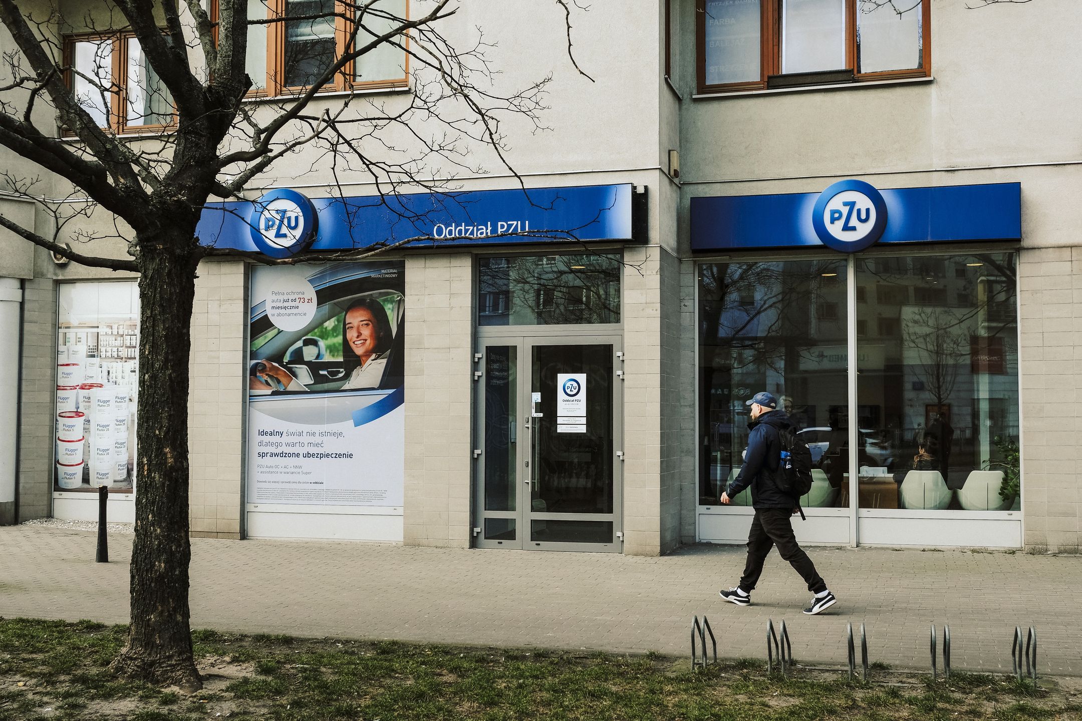 A pedestrian passes a Powszechny Zaklad Ubezpieczen SA (PZU) bank branch in Warsaw, Poland, on Monday, March 20, 2023. Poland's February retail sales fell 5% as prices rose 10.8% from a year earlier, data from the Central Statistical Office in Warsaw shows. Photographer: Damian Lemaski/Bloomberg via Getty Images