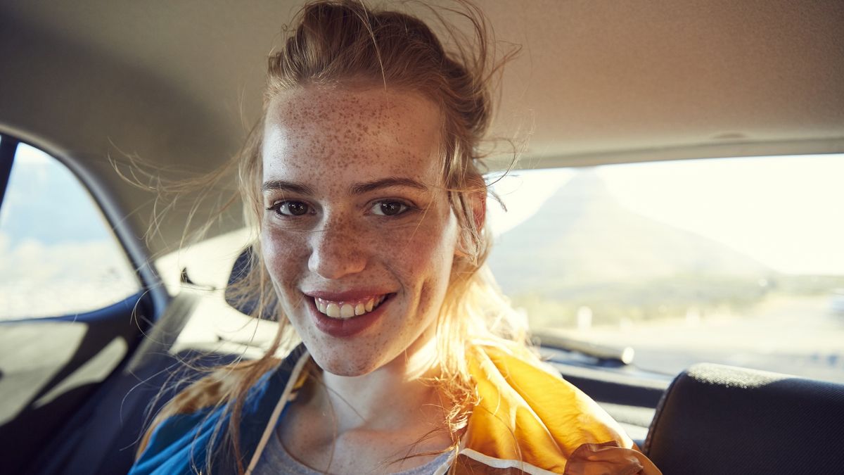 Na zdjęciu młoda kobieta siedząca na siedzeniu z tyłu samochodu