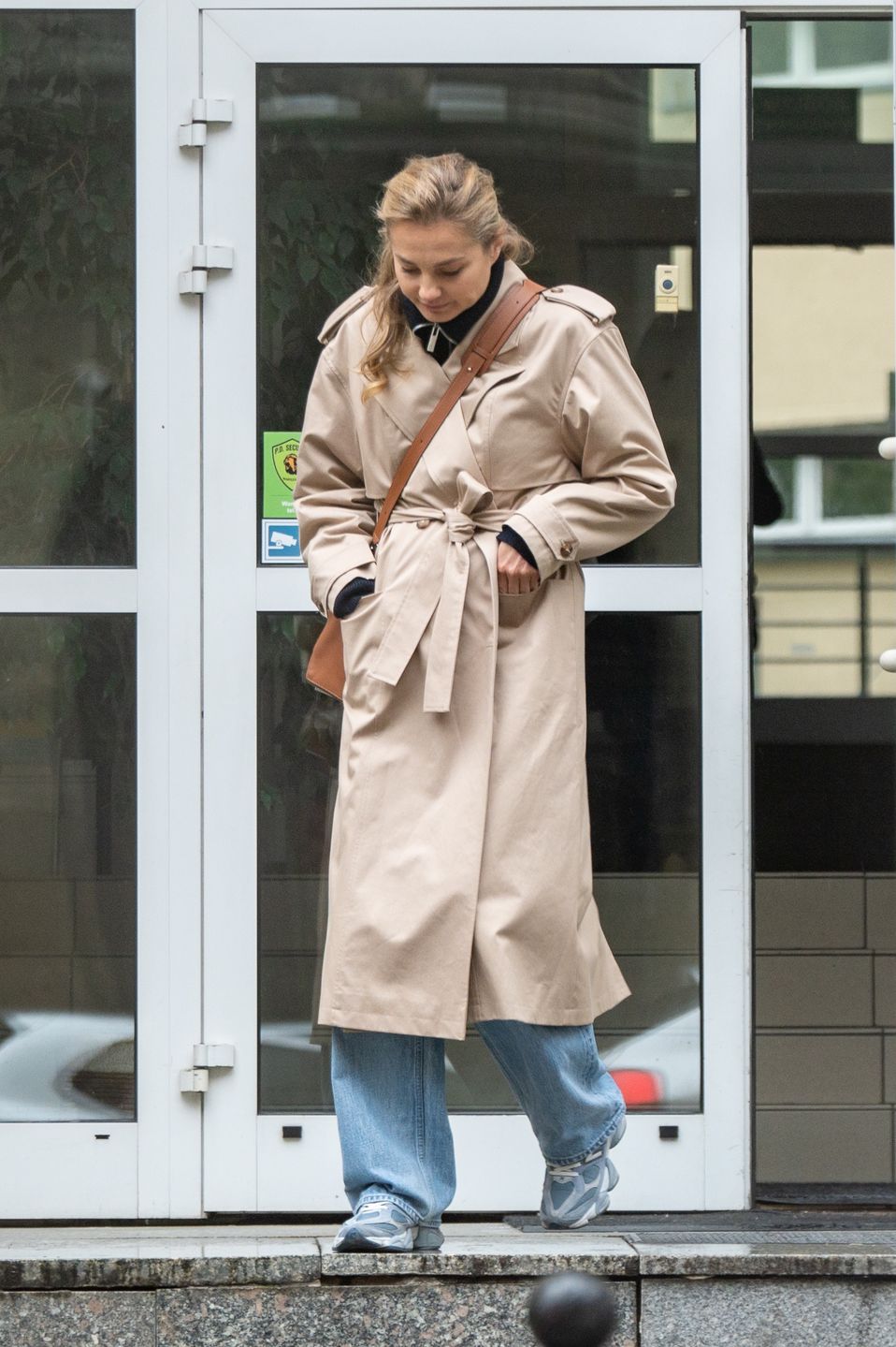 Małgorzata Socha maszeruje po deszczowej Warszawie ze smartfonem przy uchu