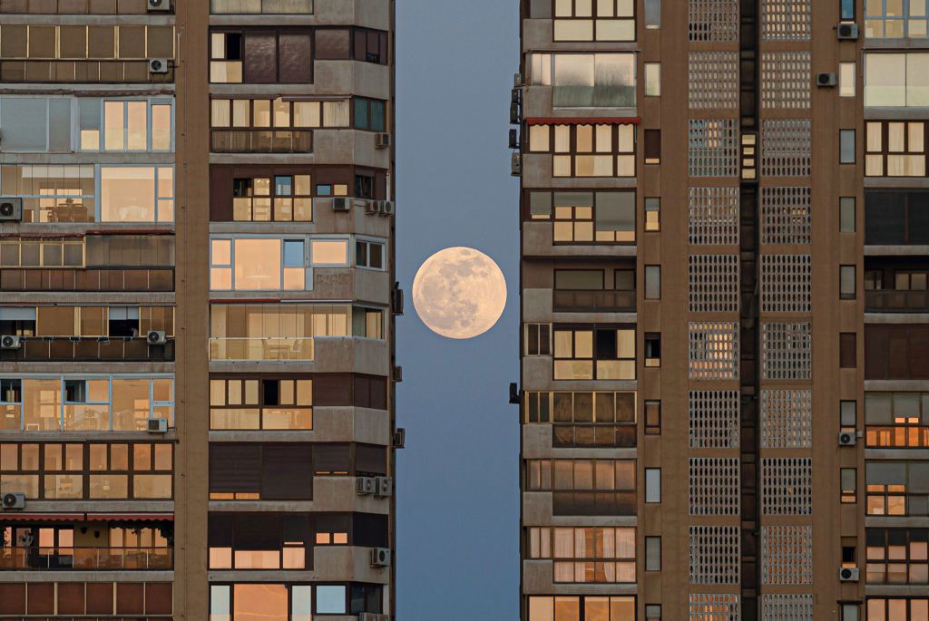 Pełnia Księżyca, zwana "Krwawym Księżycem", widziana w Maladze w Hiszpanii między budynkami przed całkowitym zaćmieniem