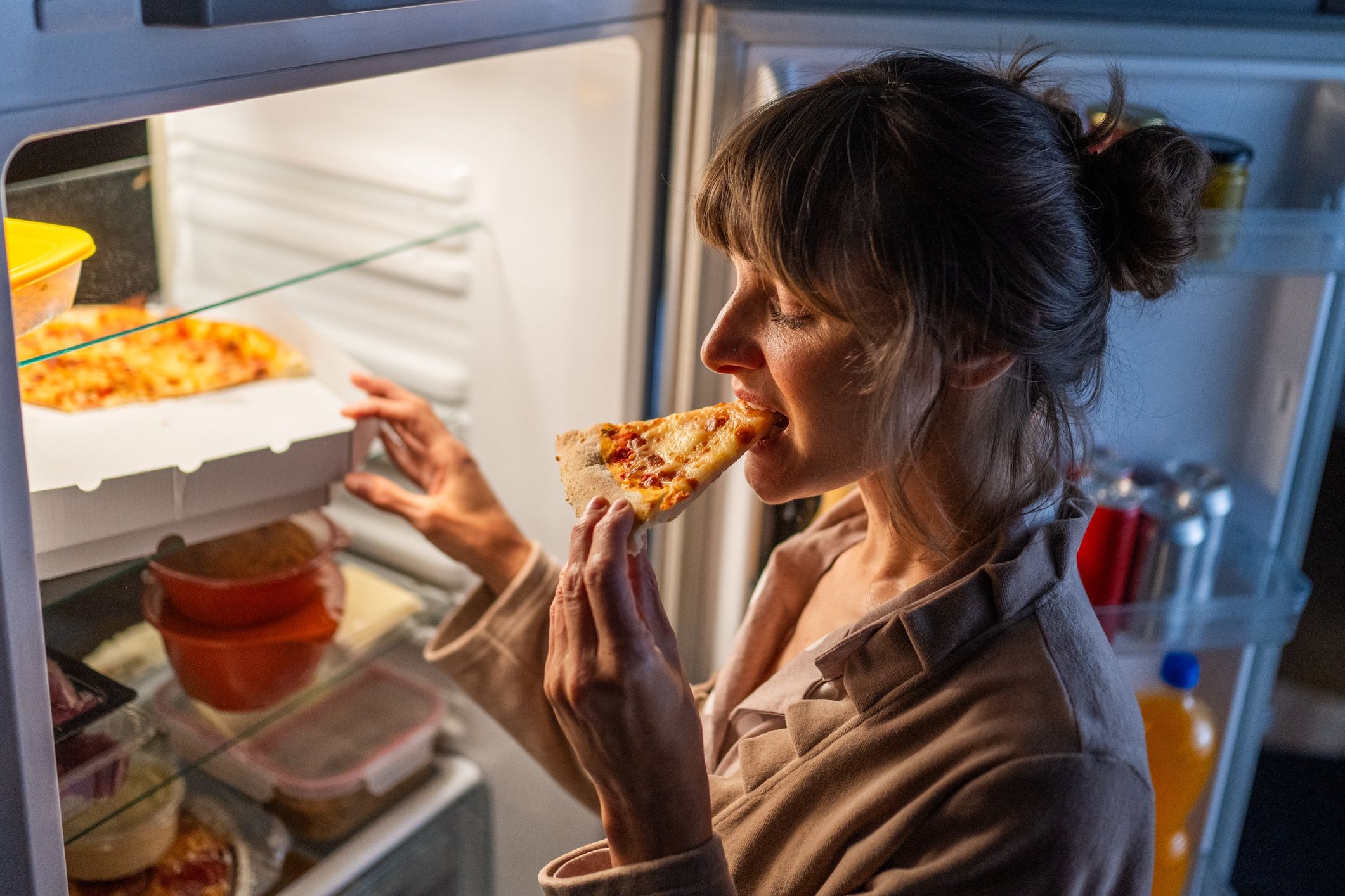 Woman eating pizza
Mature woman eating pizza while standing near open refrigerator at home.
simonkr