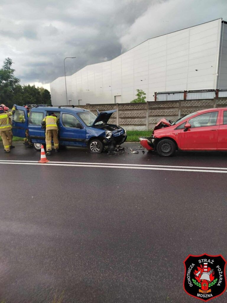 Ratownicy medyczni udzielają pomocy poszkodowanym w wypadku drogowym na ruchliwej ulicy obok dużego magazynu.