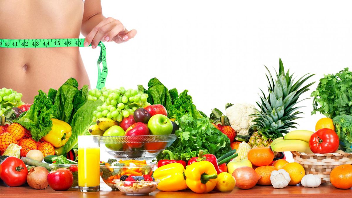 Zdjęcie przedstawia kobietę mierząca się w pasie oraz owoce i warzywa