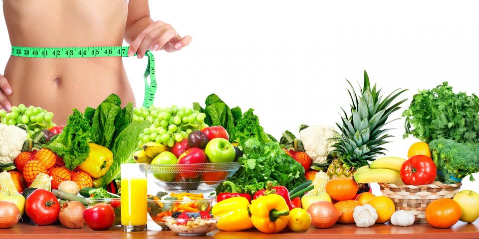 Zdjęcie przedstawia kobietę mierząca się w pasie oraz owoce i warzywa