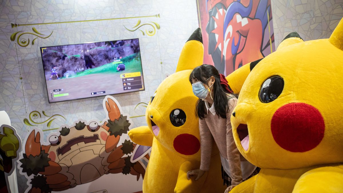 BANGKOK, THAILAND - 2022/10/22: A visitor poses for a picture with two Pikachu mascots at the Pokemon booth promoting the new "Pokemon Scarlet" and "Pokemon Violet" video game. Thailand Game Show 2022 is the largest gaming exhibition in Thailand with the latest games on the market, video game giants like Nintendo, Sega, Sony Playstation, and Microsoft were there to present their current and upcoming video games. (Photo by Guillaume Payen/SOPA Images/LightRocket via Getty Images)