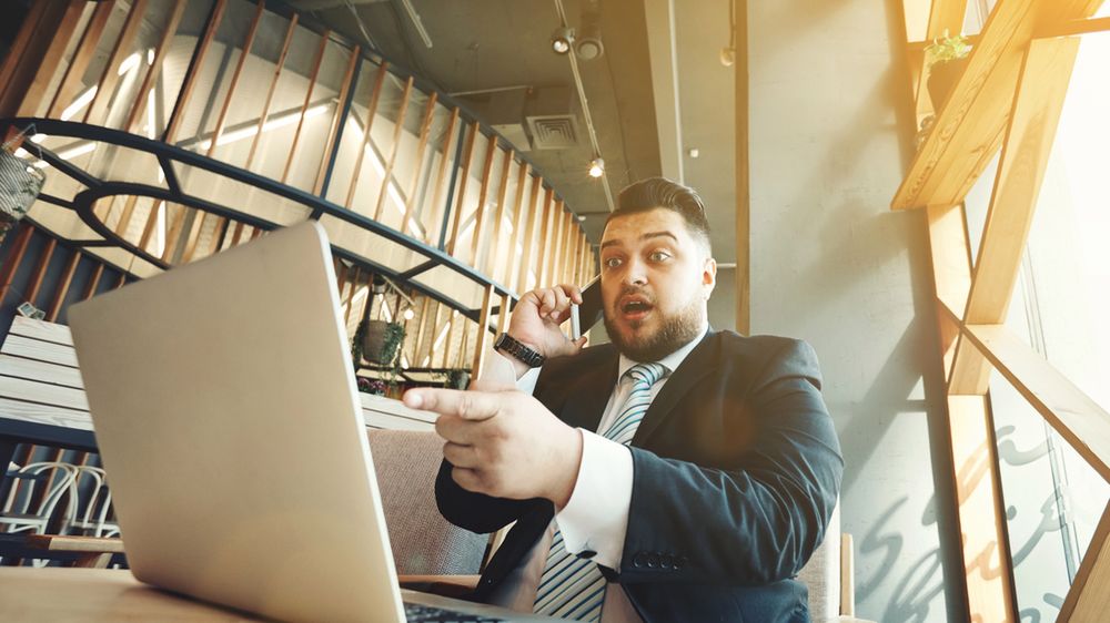 Zdziwiony biznesmen przy laptopie z depositphotos