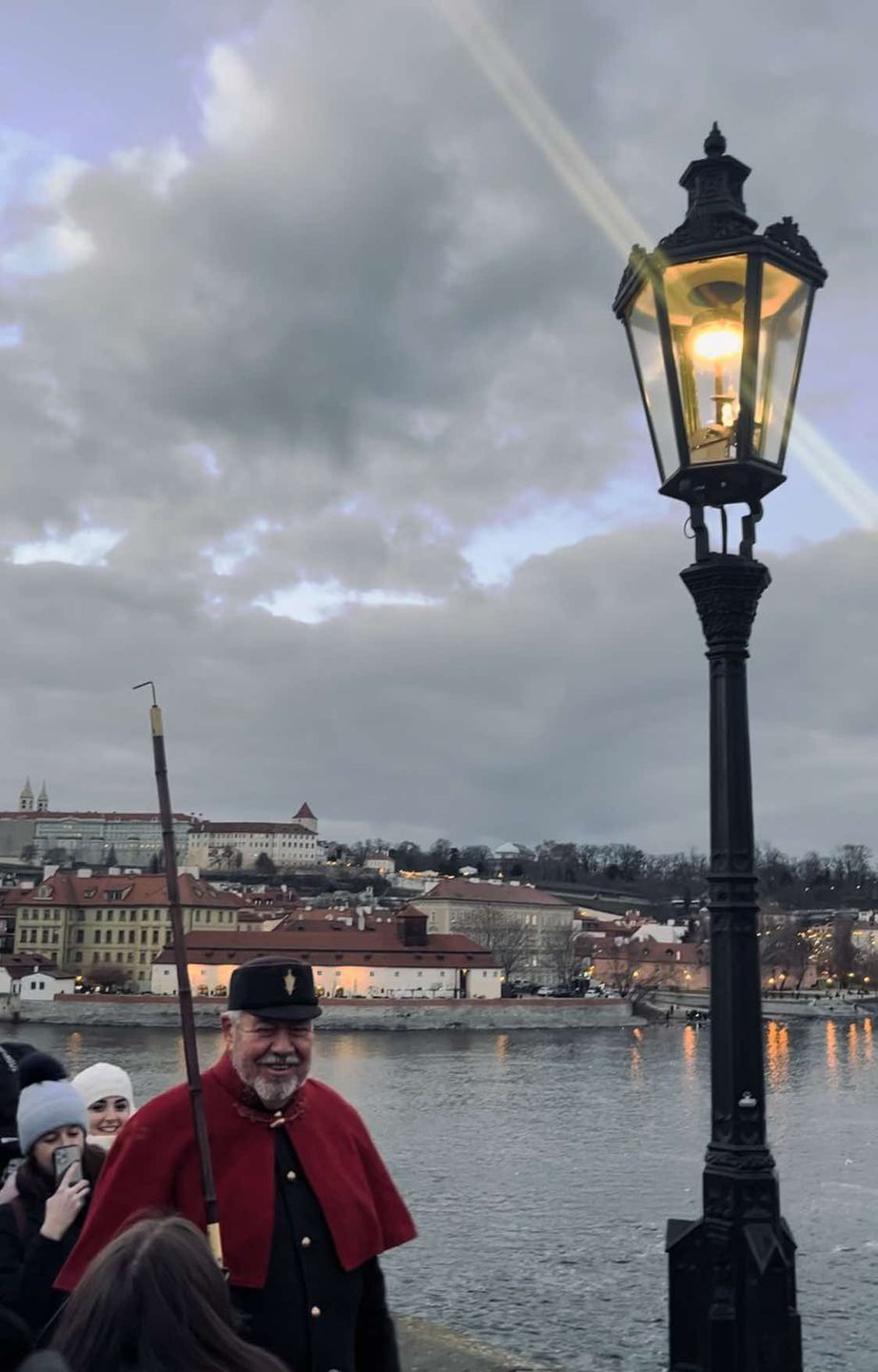 Latarnik zapala latarnie na Moście Karola