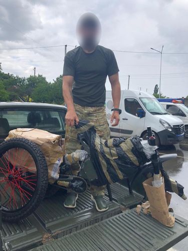 Ukraiński żołnierz rozpakowuje rower elektryczny Russell Nitro.