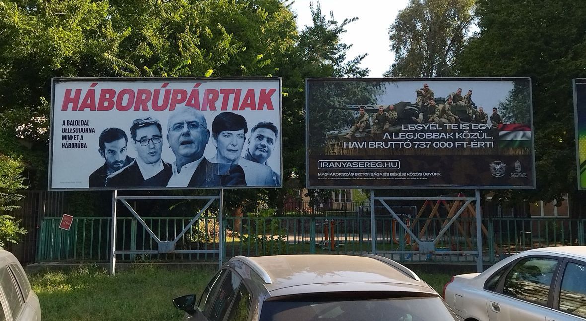 Dwa rządowe billboardy na ulicach Budapesztu. Ten po lewej przedstawia polityków opozycji i ostrzega: "Oni są za wojną. Lewica wciągnęłaby nas w konflikt". Ten po prawej zachęca do wstąpienia do armii: "Bądź jednym z najlepszych za 737 000 forintów brutto. Bezpieczeństwo Węgier naszym wspólnym celem"