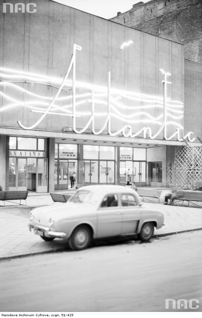 Widok zewnętrzny kina Atlantic w Warszawie. Na pierwszym planie stoi samochód osobowy marki Renault Douphine.
