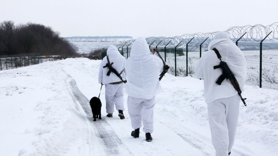 Hoptivka- ukrai?sko-rosyjskie przej?cie graniczneKHARKIV REGION, UKRAINE - FEBRUARY 16, 2022 - Three border guards in snow camouflage uniforms and a black service dog are on a patrol mission at the Ukraine-Russia border, Kharkiv Region, northeastern Ukraine.Vyacheslav Madiyevskyy