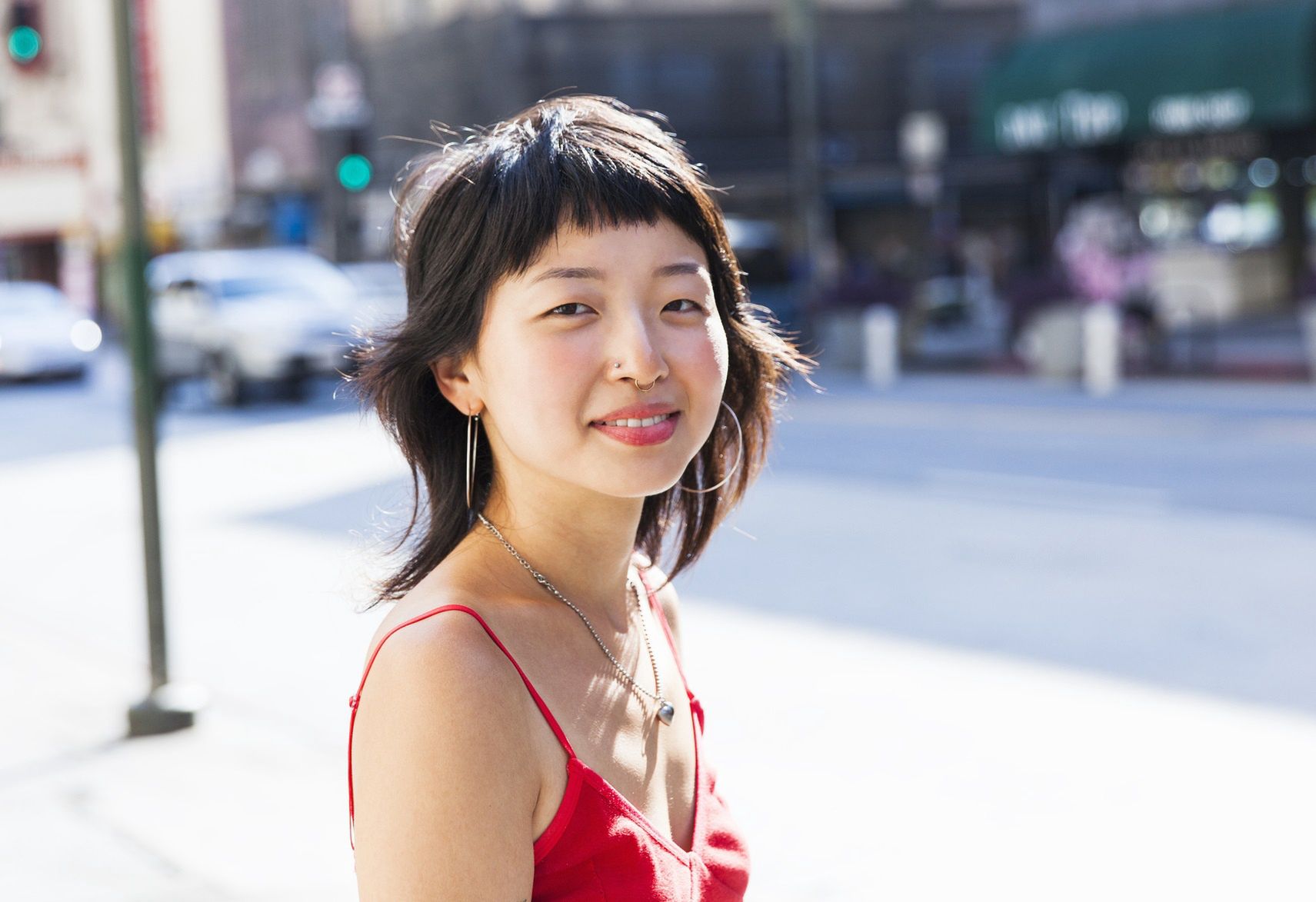 Young woman looking at camera smiling
Young Asian woman with a rose ring looking at the camera smiling with a city street scene out of focus in the background
Stephen Zeigler