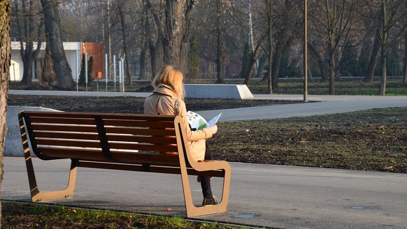 Kobieta czytająca gazetę na ławce w Parku Ludowym