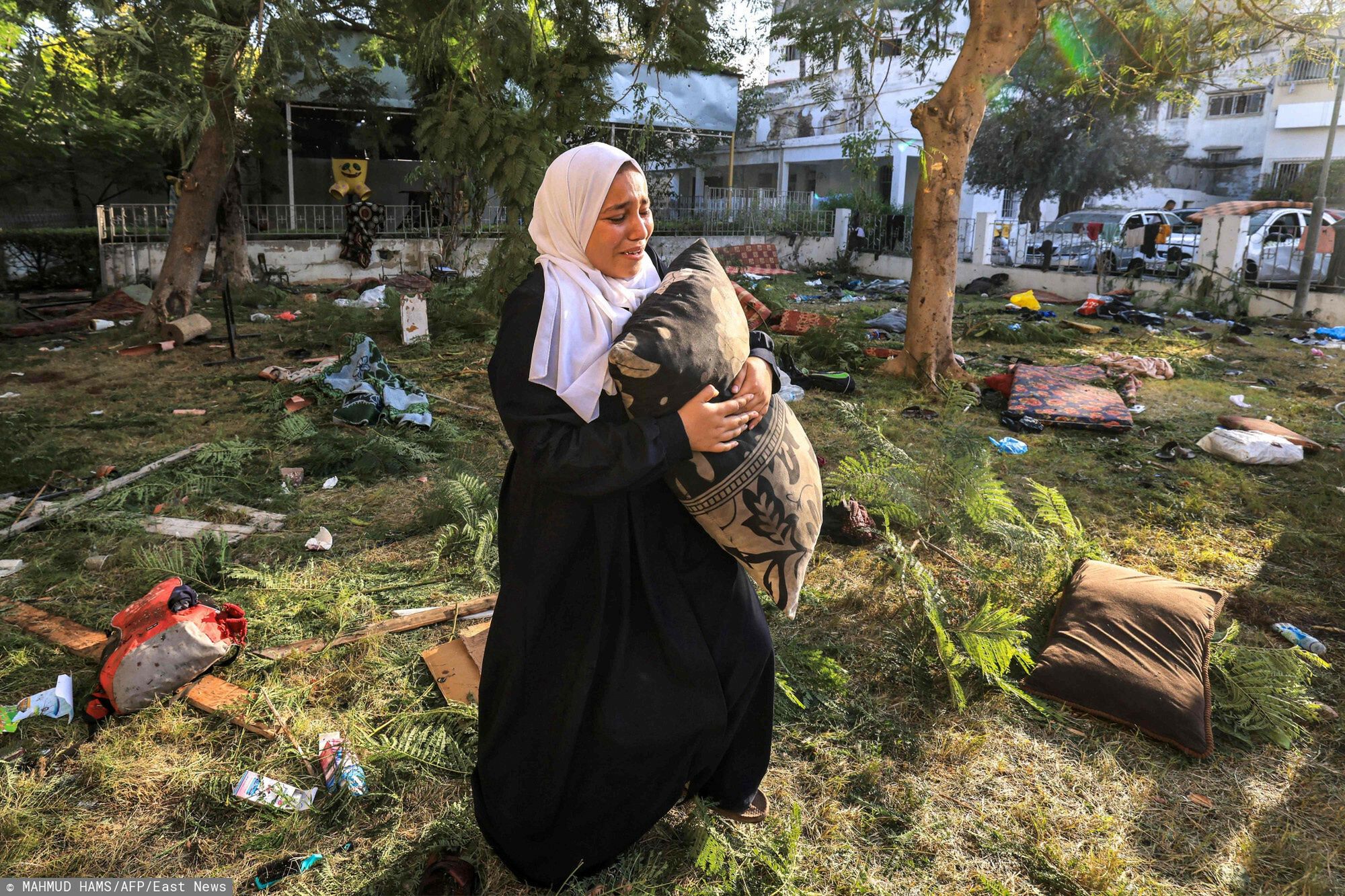 Temporary
A woman reacts while holding a pillow as she stands amidst debris outside the site of the Ahli Arab hospital in central Gaza on October 18, 2023 in the aftermath of an overnight blast there. A blast ripped through a hospital in war-torn Gaza killing hundreds of people late on October 17, sparking global condemnation and angry protests around the Muslim world.  Spokesman Hagari told a press briefing that at the time of the incident, the Israeli army was not conducting air operations near the hospital and the rockets that hit the building did not match theirs. (Photo by MAHMUD HAMS / AFP)
MAHMUD HAMS