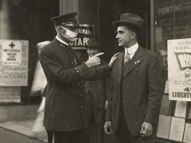 Policjant w San Francisco zwraca uwagę mężczyźnie na brak maseczki podczas pandemii hiszpanki (1918).