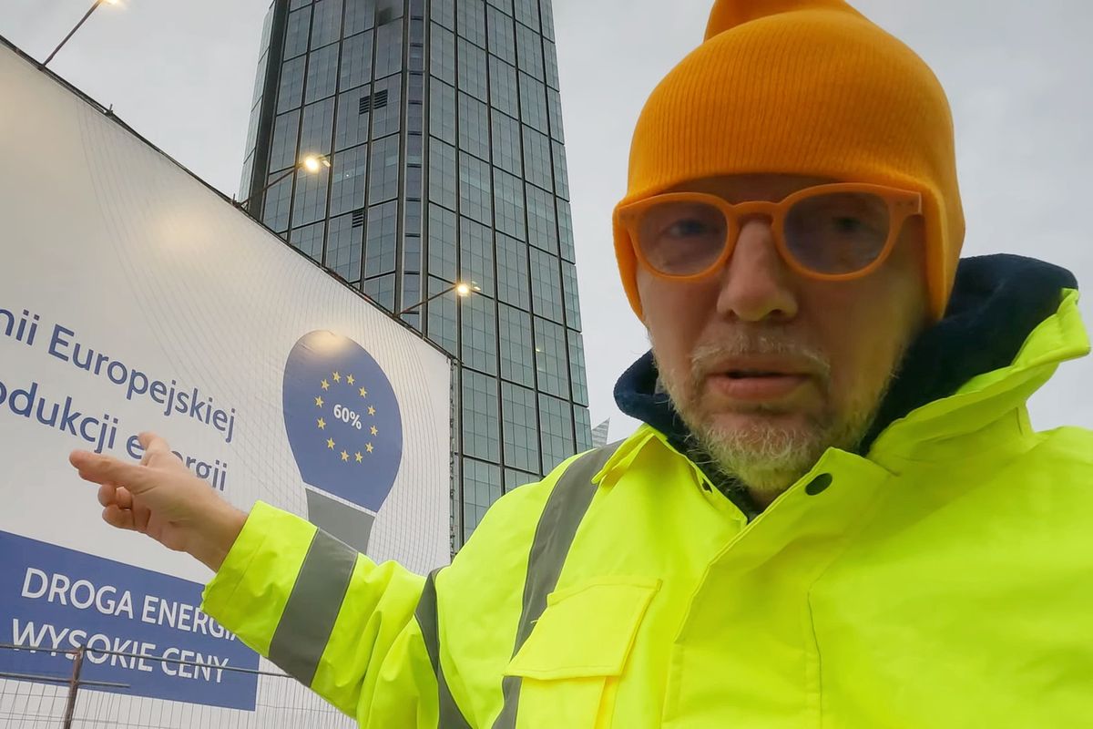 Marcin Mizgalski na tle słynnej kampanii billboardowej o rzekomej drożyźnie spowodowanej przez politykę klimatyczną Unii Europejskiej