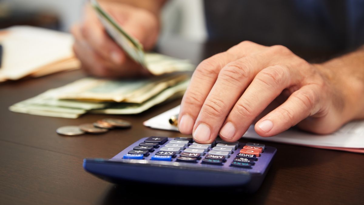 Close-up of a person's hand using a calculator and counting money
Thanasis
