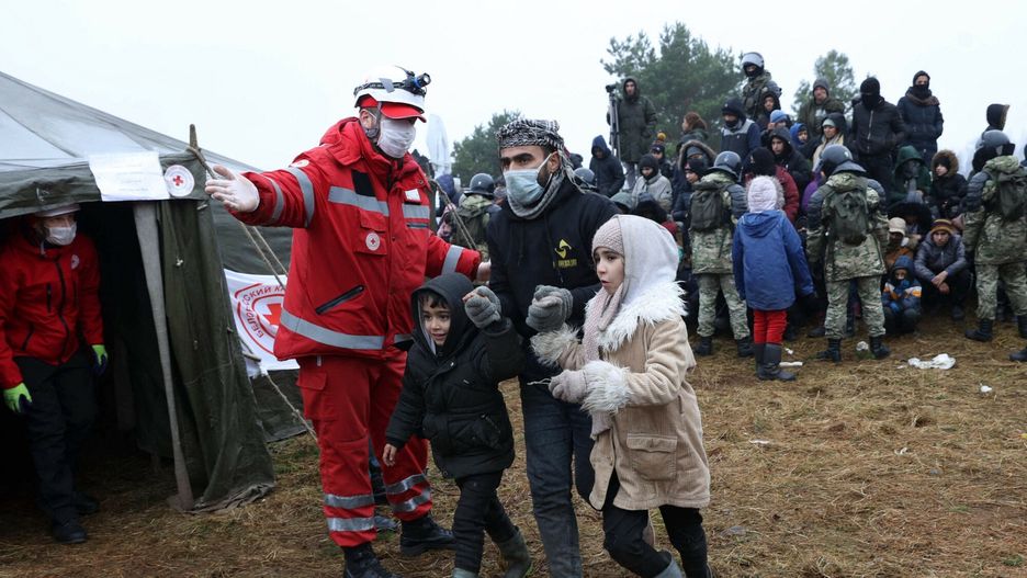 Członkowie Białoruskiego Czerwonego Krzyża wskazują drogę migrantom podczas dystrybucji pomocy humanitarnej w obozie w pobliżu granicy białorusko-polskiej w obwodzie grodzieńskim 14.11.2021 r