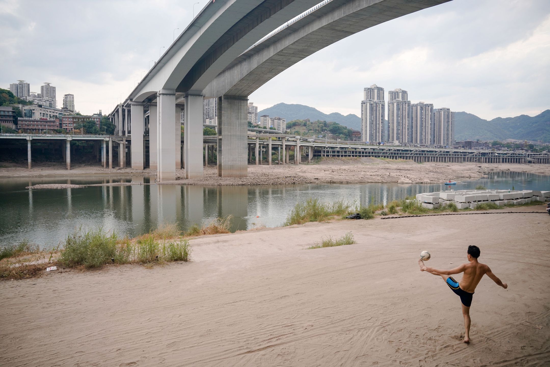Daily life in Chongqing while drought is coming to an endepa10143933 A man plays soccer on the shore of the Jiangling river, a major tributary of the Yangtze River, in Chongqing, China, 28 August 2022 (issued 29 August 2022). According to a report by the Chongqing Meteorological Bureau issued on 26 August, it is expected that the long-awaited cooling and wet weather will gradually arrive beginning 29 August, and that the daily maximum temperature in most areas of Chongqing will gradually drop to below 35 Celsius degrees, and terminates the current round of high-temperature weather in Chongqing.  EPA/WU HAO Dostawca: PAP/EPA.WU HAO