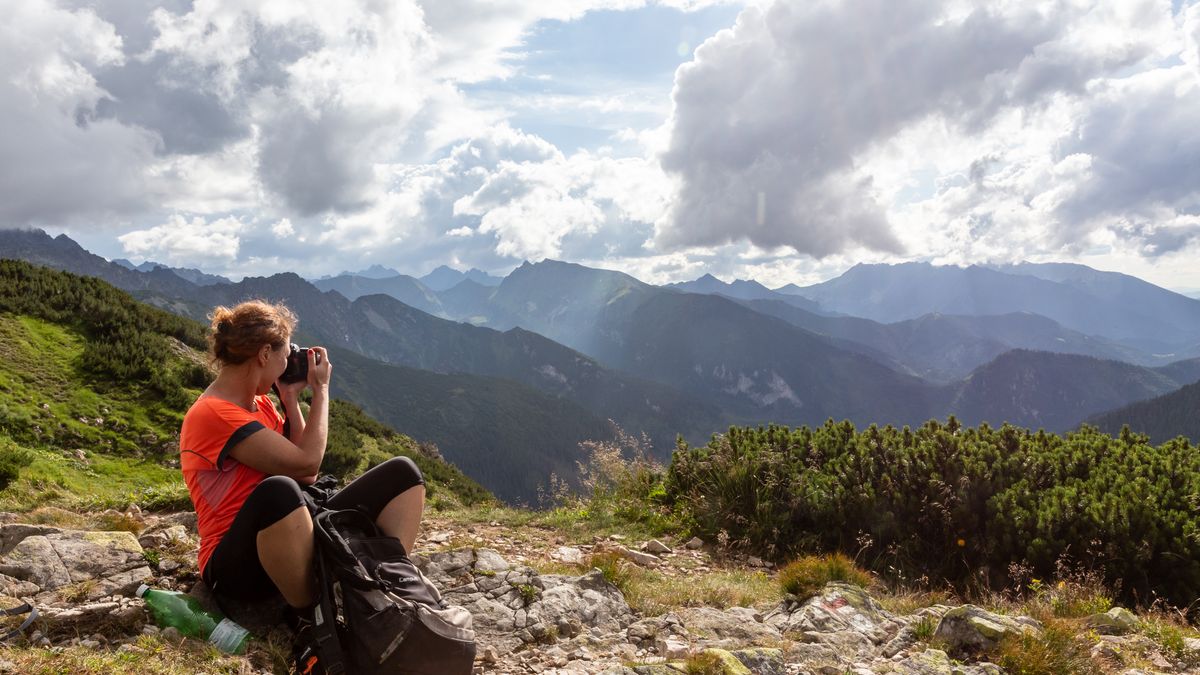 A tourist takes a photograph after reaching a summit in Tatra mountains in Northern Slovakia on August 2, 2025. Tatra National Park mountains are very overcrowded. Tourists sometimes wait in a queue to reach a summit. (Photo by Dominika Zarzycka/NurPhoto via Getty Images)