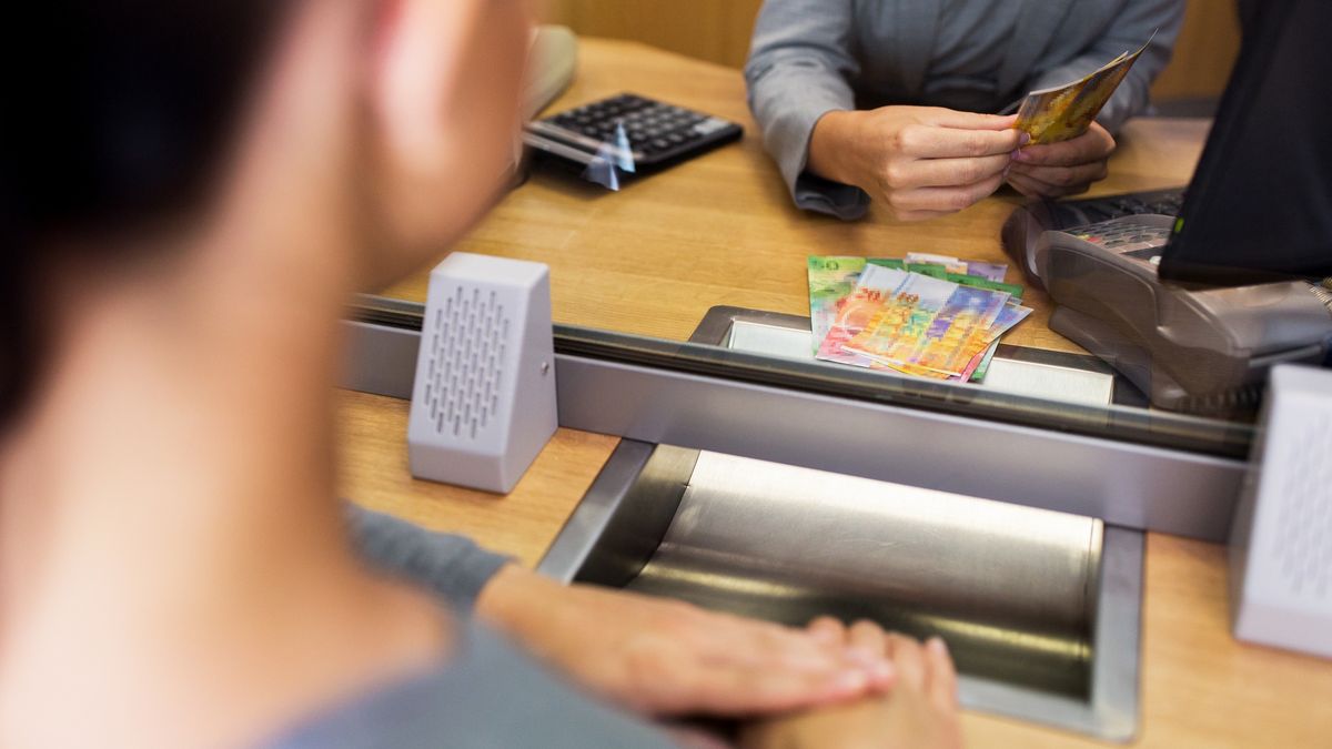 Na zdjęciu kobieta przed okienkiem w kantorze pobierająca franki szwajcarskie