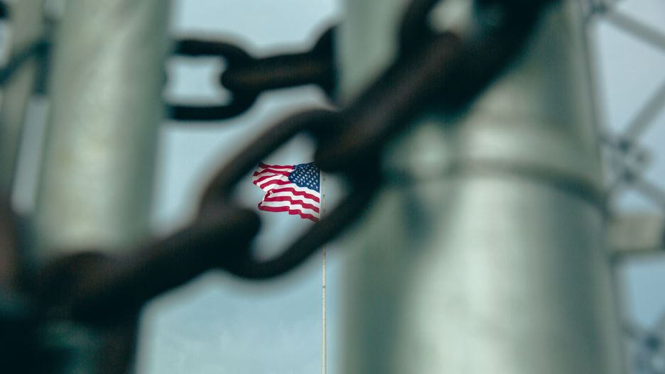 GUANTANAMO BAY, CUBA - JUNE 27: (EDITORS NOTE: Image has been reviewed by the U.S. Military prior to transmission.)  An American flag flies behind barbed wire fencing at the Office of Military Commissions building on June 27, 2023 at Guantanamo Bay, Cuba. At the prison within Naval Station Guantanamo Bay where media members are no longer allowed, 30 men still remain imprisoned while five separate war crime prosecutions involving some of the detainees proceed within Guantanamo's war court  none have yet reached a trial date. (Photo by Elise Swain/Getty Images)