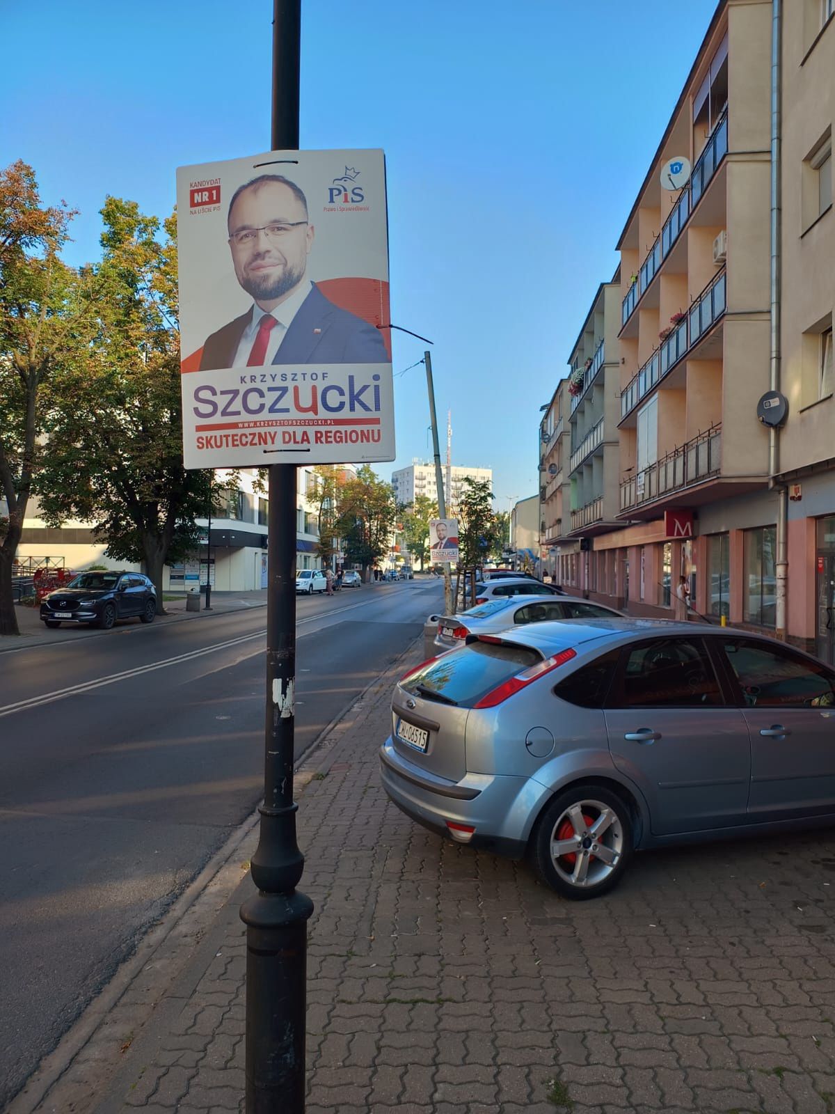 Plakat wyborczy Krzysztofa Szczuckiego we Włocławku na miejskim słupie przy drodze