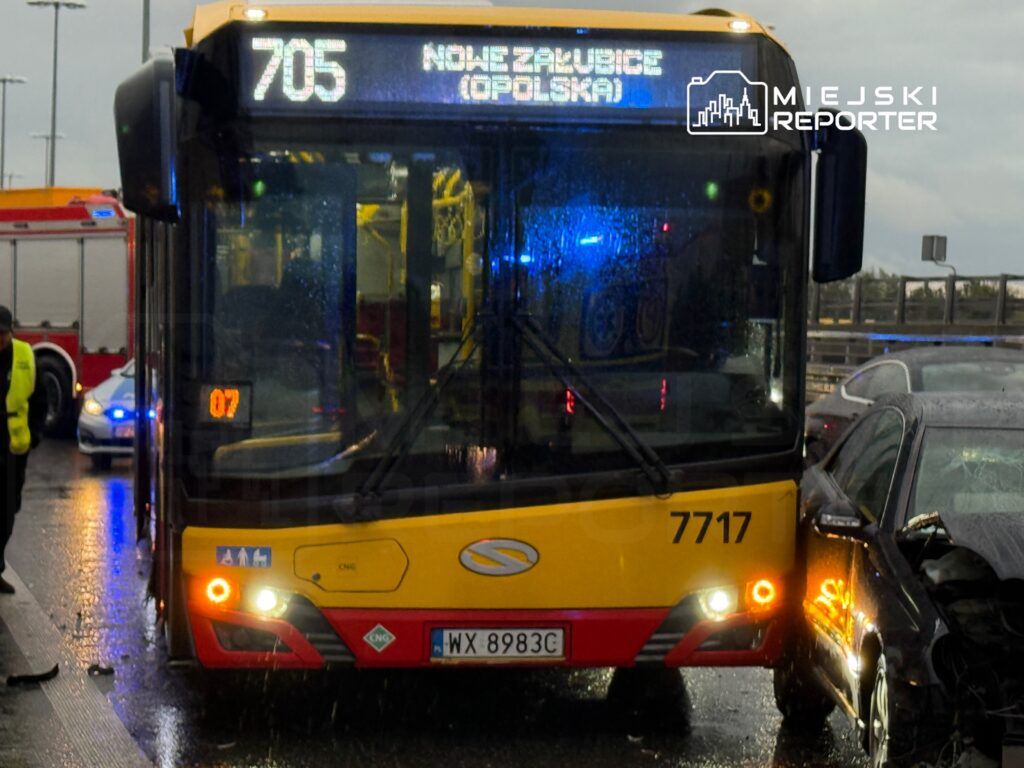 Autobus linii 705 z napisem "NOWE ZABŁUDOWICE (OPOLSKA)" stoi na mokrej jezdni, obok niego widać uszkodzony czarny samochód.