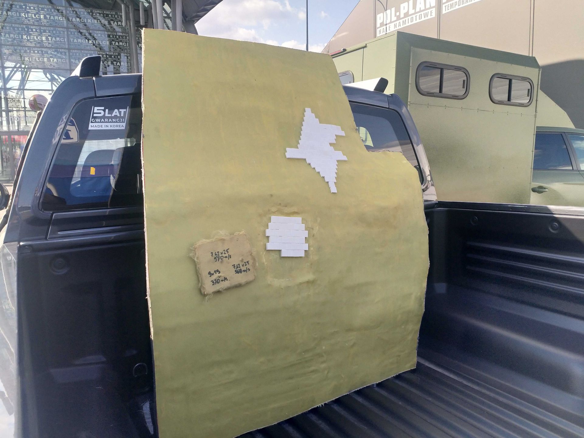 Wycinek pokazujący budowę pancerza obejmujący UHMWPE, kevlar oraz kostki ceramiki. 