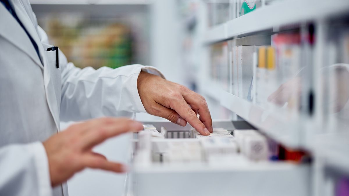 Side view of a male hands, searching for something from the drawer, working as a pharmacist.Male pharmacist choosing a medicine from the drawer, side view.nortonrsx