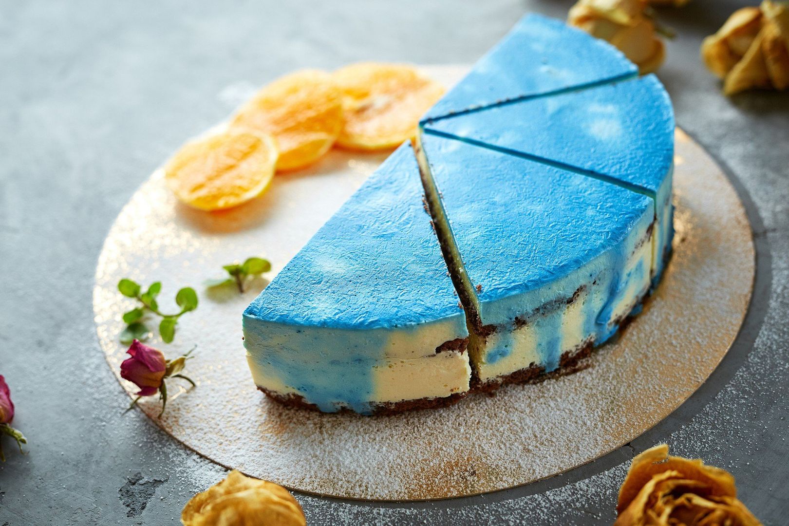 half of cutted mousse cake with blue glaze on a dark gray concrete background