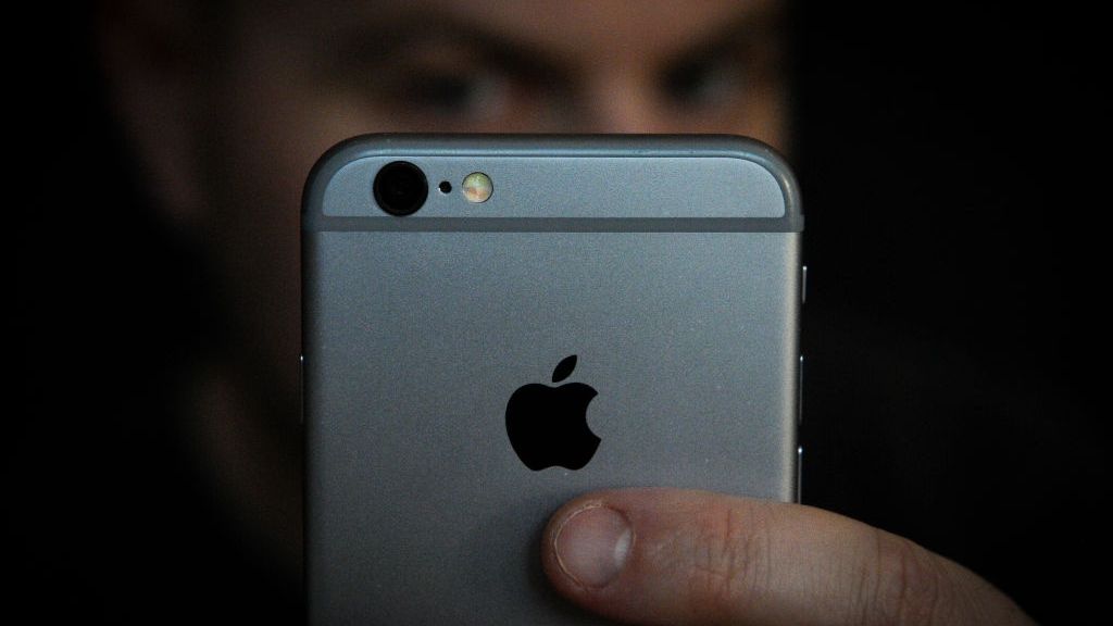 Mężczyzna zasłaniający twarz iPhonem